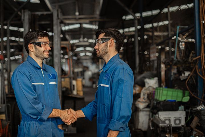 two men shaking hands inside a factory